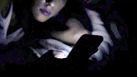 Dimly lit babe in bed holding phone, teasing with Ricky Johnson and Tyler Knight action
