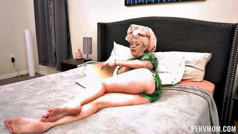 Blonde MILF in sheer green lingerie spreads legs wide on bed teasing her shaved pussy
