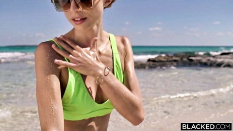 Emelie Crystal in green bikini applying sunscreen on beach