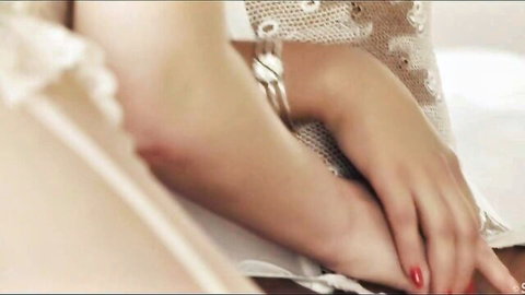 Closeup of woman's sexy red-nailed hands crossed in sheer lace lingerie teasing