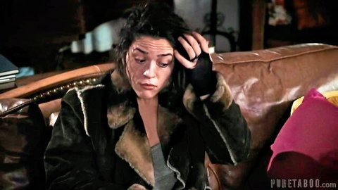 Upset brunette in fur jacket sits distressed on leather couch in taboo scene