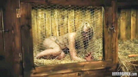 Naked blonde MILF trapped in hay-filled barn cage reaching out desperately in horror porn