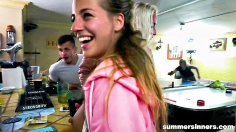 Blonde woman in pink hoodie smiles at wild party turning into orgy with tattoos and blowjobs