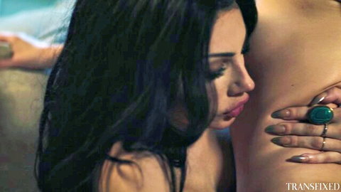 Seductive brunette with plump lips passionately kissed on neck by topless beauty with turquoise ring