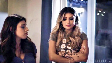 Brunette and blonde women in tense talk, casual tops and tattoos