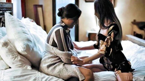 Two Asian women in intimate touch, one in sweater, one in floral dress