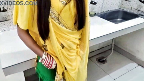 Seductive Indian wife in yellow saree posing in kitchen