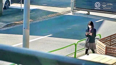 Meguri Minoshima in school uniform standing outdoors, checking phone