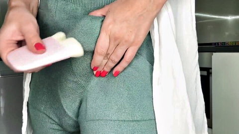 Stepmom in tight green leggings holds pink toy near crotch, teasing intimately