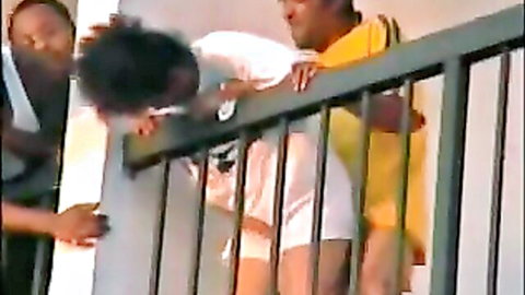 Ebony babe bent over balcony railing getting fucked doggystyle by black stud while another watches