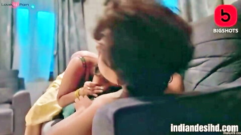 Indian housewife in yellow top leans over kissing man's neck on couch in Bigshots episode