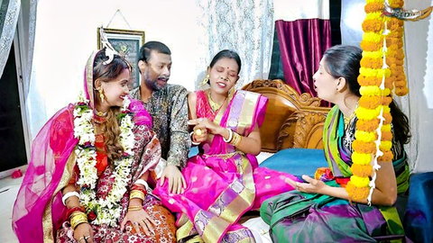 Indian bride in red saree with family women in colorful sarees during wedding ritual