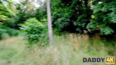 Lush green forest outdoor scene with tall grass and pole in Daddy 4K daddy roleplay video