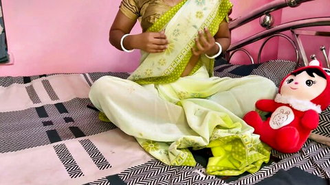 Desi Indian Bhabhi in green saree sitting on bed, teasing pose