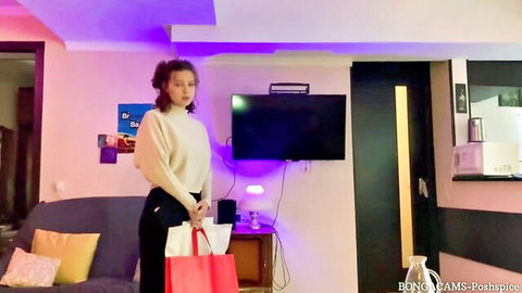 Young curly-haired student in sweater and pants teases rent payment with ass