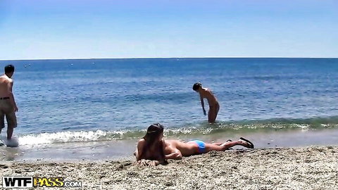 Hot college babe topless in blue bikini on sunny beach with nude guys