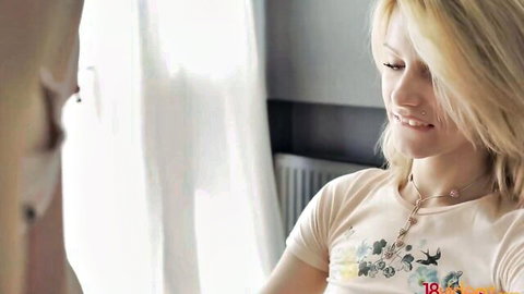 Sexy blonde teen with piercing smiling seductively in floral t-shirt close-up
