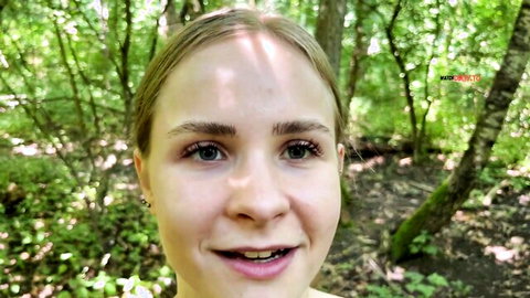 Blonde teen smiling with open mouth in sunny forest outdoors