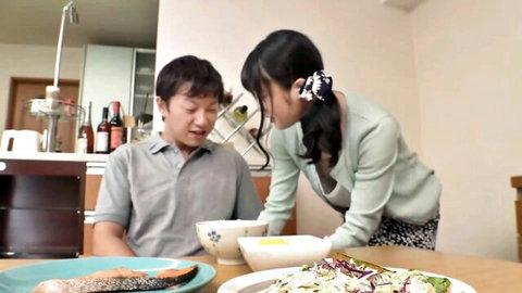Japanese step-sister leans close to step-brother at table in teasing pose