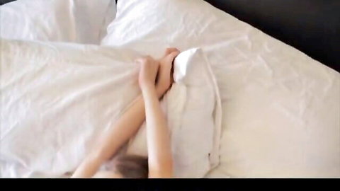 Skinny young teen girl passionately clutching white sheets on bed with bare feet exposed