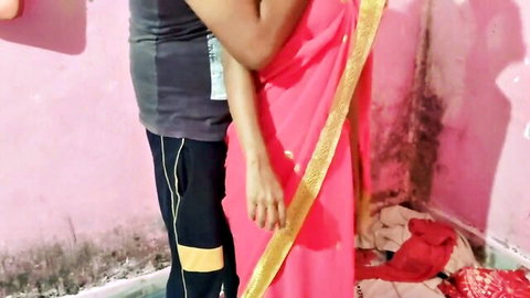 Indian woman in pink sari intimately embraced by man from behind