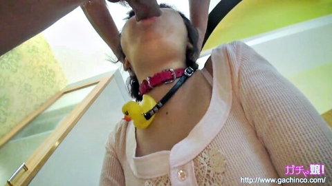 Asian babe in pink sweater with red collar and yellow rubber duck forced mouth open by hand