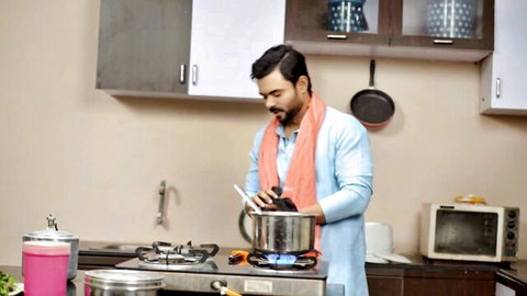 Man in traditional attire cooking in kitchen
