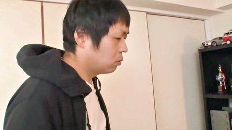 Japanese man in black hoodie looks sideways in bedroom with toy car models on shelf