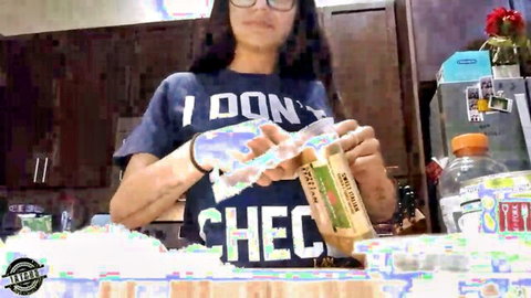 Brunette with glasses holding Chex cereal boxes in kitchen smiling at webcam