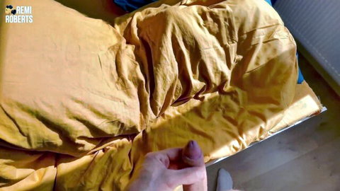 Woman's hand with pink nails pinches her hard pink nipple on yellow bedsheets