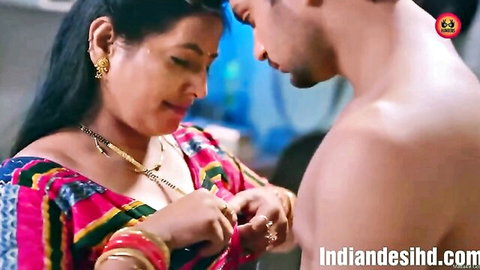 Indian mature brunette in colorful saree touches shirtless young man intimately
