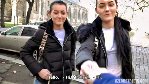 Twin Czech teens in jackets wave hello to Michael on rainy street