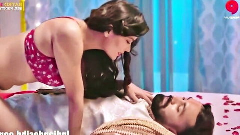 Indian MILF in pink floral bra passionately kisses bearded man while straddling him on bed