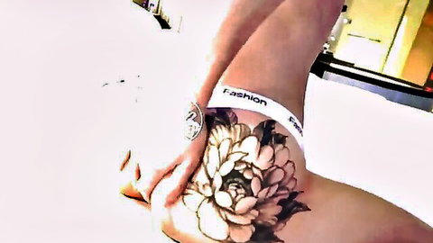 Tattooed Asian woman's thigh with peony ink, sexy close-up pose