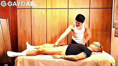 Blindfolded muscular Asian man gets thigh massage from shirtless masseur
