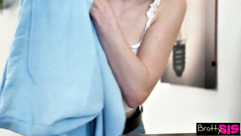 Myra Moans holds blue hoodie in low-cut white top, teasing cleavage in mirror