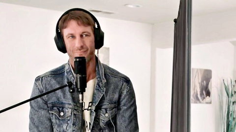 Man in denim jacket at mic, intro to Cassie Del Isla & Vivianne DeSilva threesome blind date