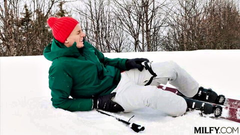 Brandi smiling after skiing fall in snow, green jacket and white pants