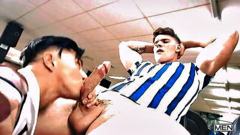 Tattooed Asian stud sucking muscular white hunk's hard cock in gym blowjob