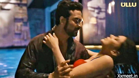 Bearded Indian man passionately embraces busty woman in red bra showing deep cleavage by pool