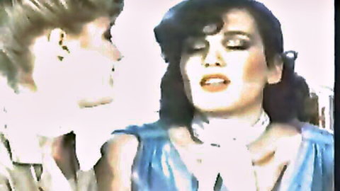 Vintage lesbian office seduction as blonde secretary gazes sensually at brunette in blue dress