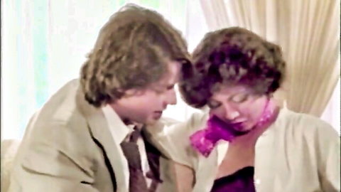 Vintage 70s couple in intimate embrace, man in suit nuzzling woman with curly hair