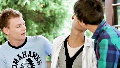 Two young guys in casual shirts share a close outdoor moment in gay threesome preview