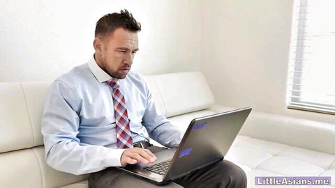Businessman in blue shirt red tie typing on laptop on white couch