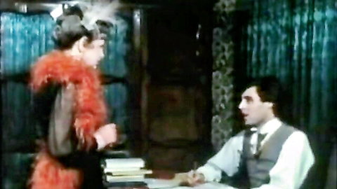 Vintage seductress in sheer black top and red feather boa flirts with suited man at office desk