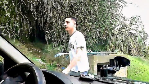 Young Latino guy in white tee leaning into car window outdoors naughty tease