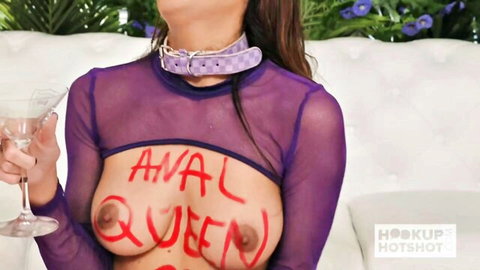 Chloe Amour as Anal Queen, breasts exposed with red body writing in sheer purple top
