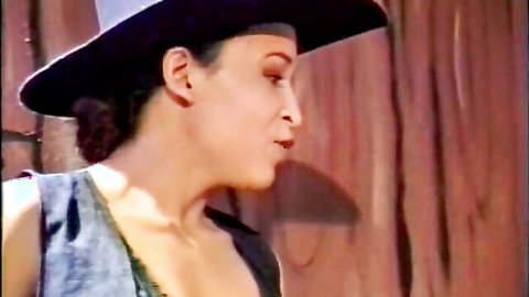 Retro brunette babe in hat and open vest showing cleavage closeup