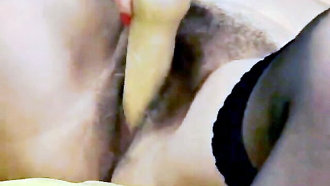 Close-up of blonde woman masturbating with yellow dildo in black stockings