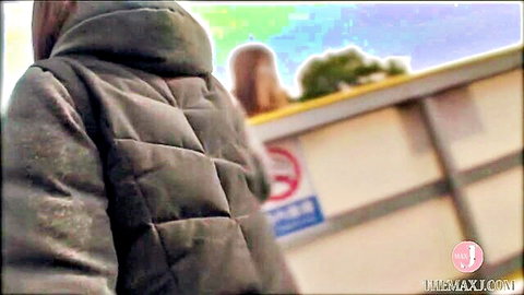 Clothed petite Asian babe in puffer jacket stands by dumpster outdoors